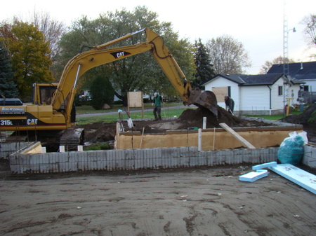 Continuing filling and packing the final layer of sand in the garage foundation.